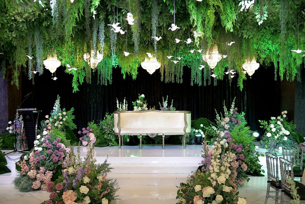 Pelamin bersofa putih dengan chandelier dan burung kertas tergantung di Bizmilla Ariz Hall Putrajaya